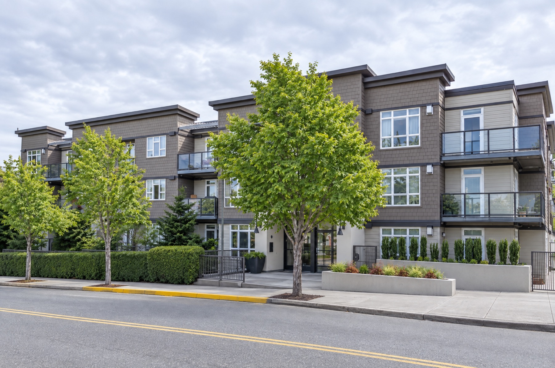128 on State Apartments in Kirkland: three-story building with balconies, boxwood hedges and street trees
